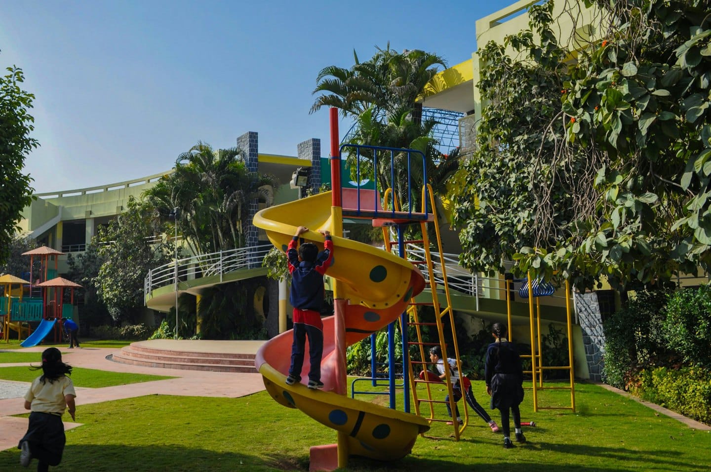 Kinder spielen auf einem sonnigen Spielplatz mit Rutsche und Klettergerüsten.