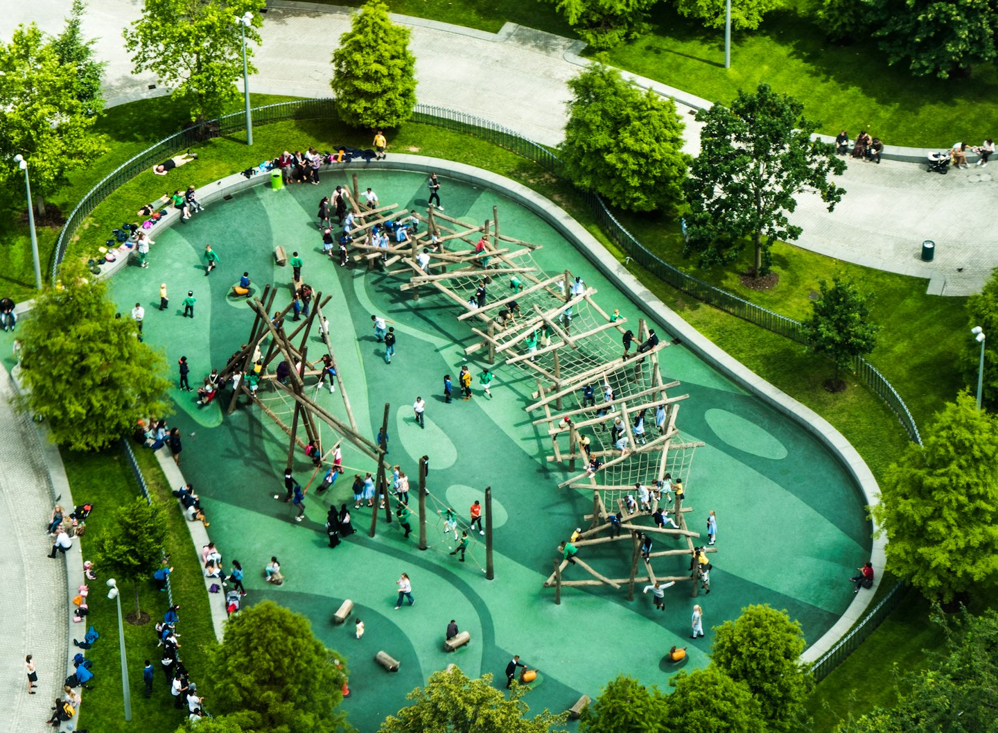 Kinder und Erwachsene spielen an einem sonnigen Tag auf einem modernen Holzspielplatz.